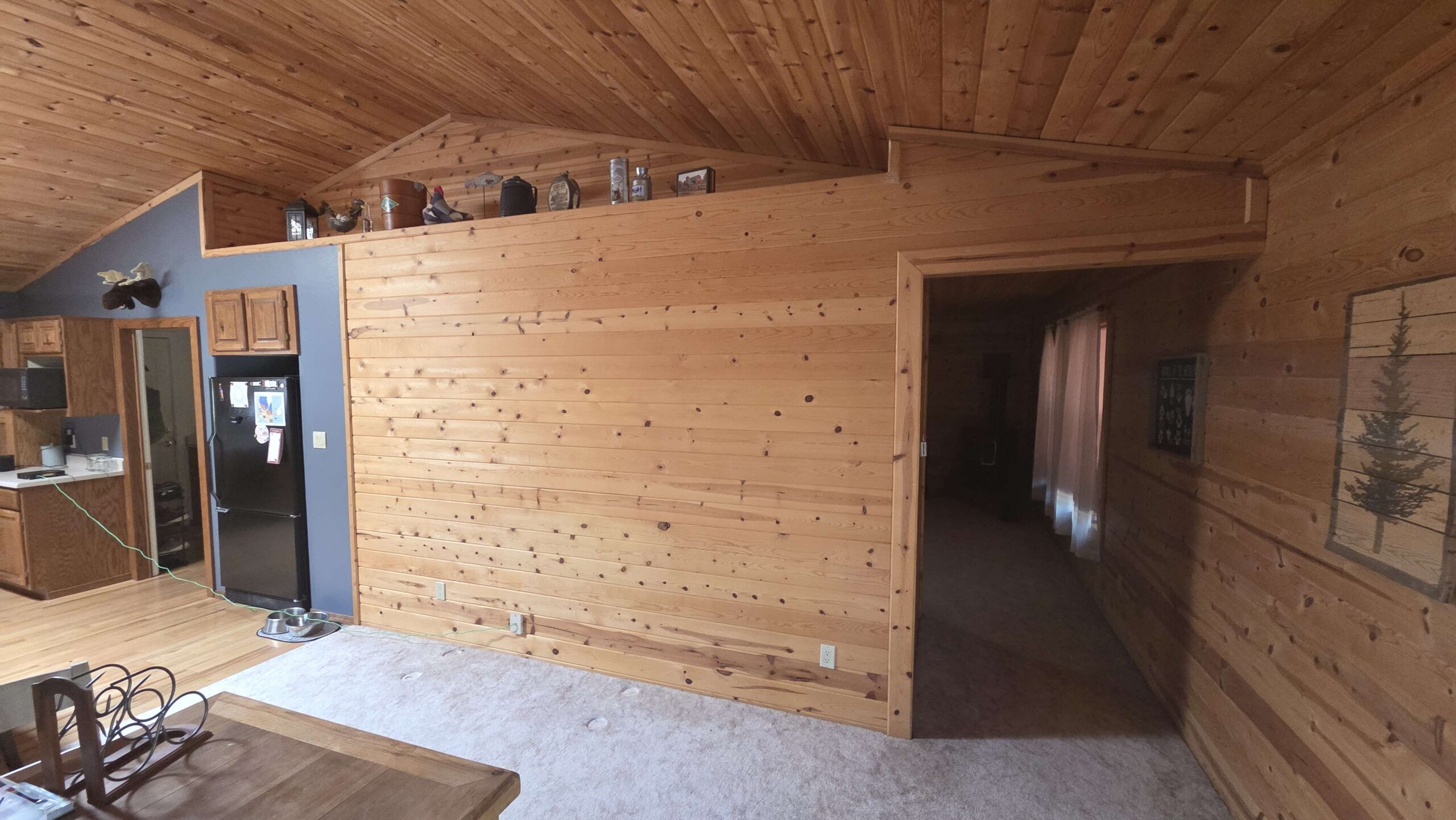 Cabin wall before: dark knotty pine and an open doorway with no door