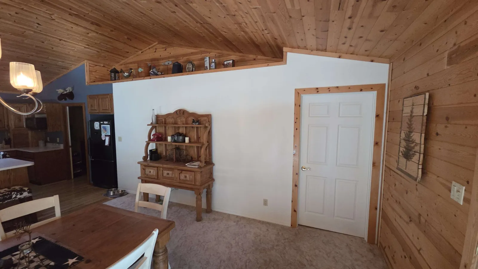 Same cabin wall after: finished drywall, fresh paint, and a new door hung and trimmed